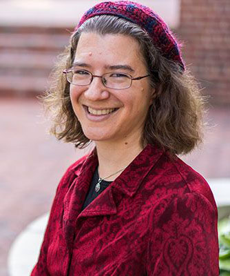 Professor Julia Watts Belser wearing a red jacket and smiling. 