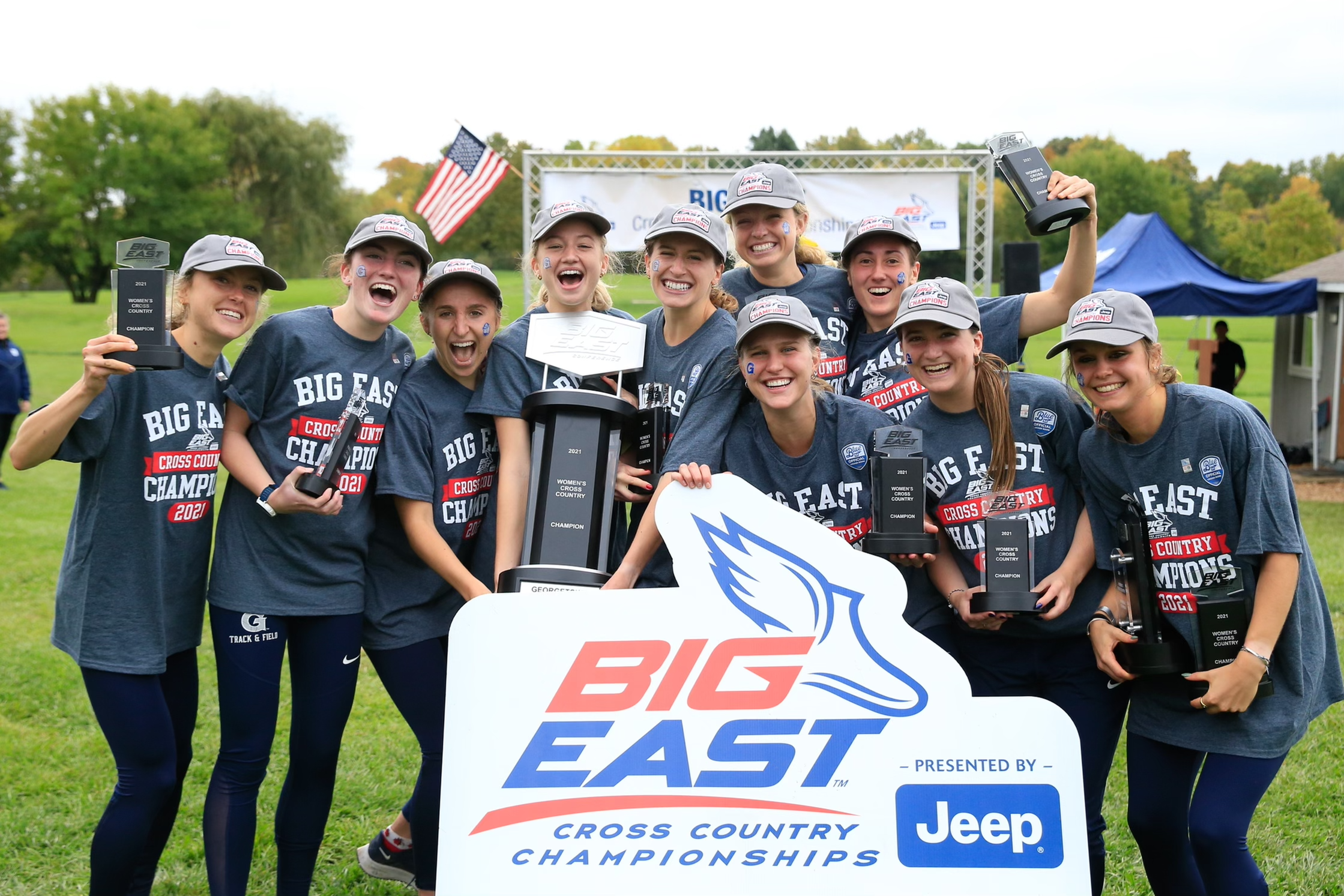 a group of women smile holding a trophy and banner saying BIG EAST