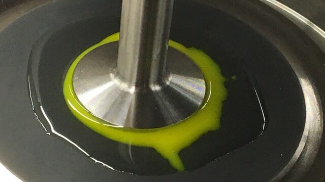 Oobleck, dyed yellow/green in the experiment, being agitated by a metal implement. 