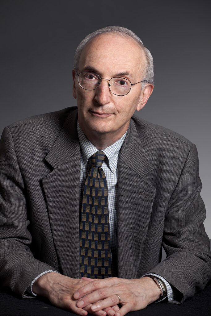A portrait of Robert Lieber wearing a patterned tie and dark gray sports coast. 