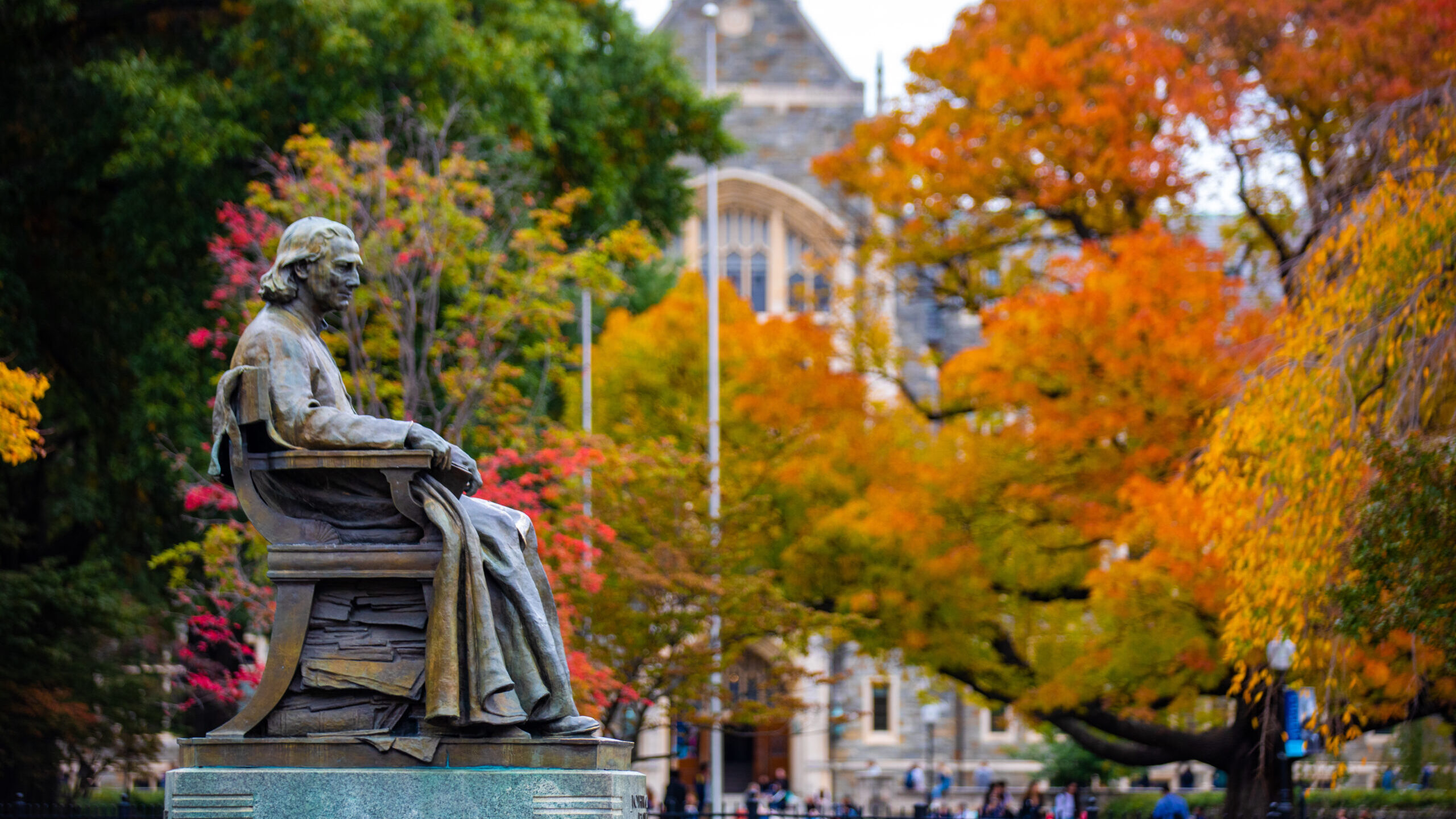 John Carroll statue on campus during the fall with leaves changing colors