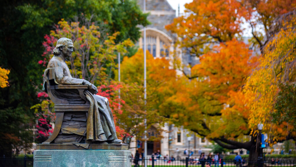 Statue of John Carroll depicted in the fall with leaves turning orange and yellow