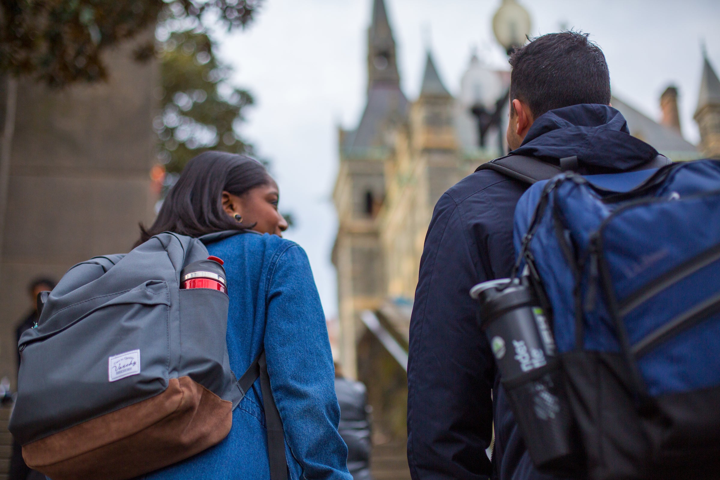 Two students wearing backpacks walking toward Healy Hall