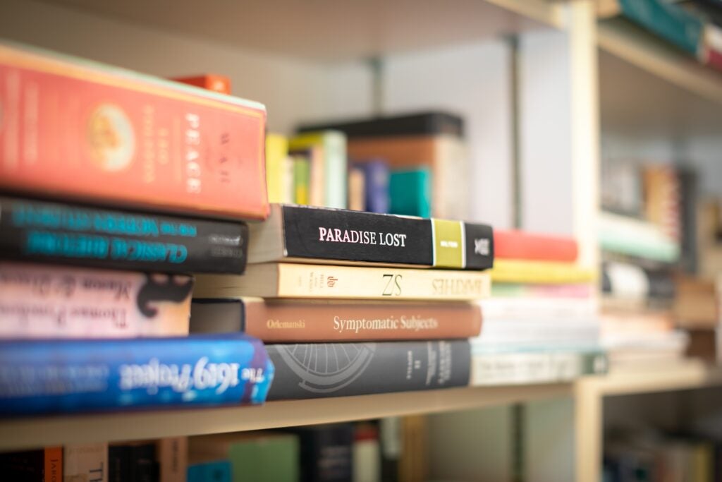 A collection of books on a shelf. The most prominent is Milton's Paradise Lost. 