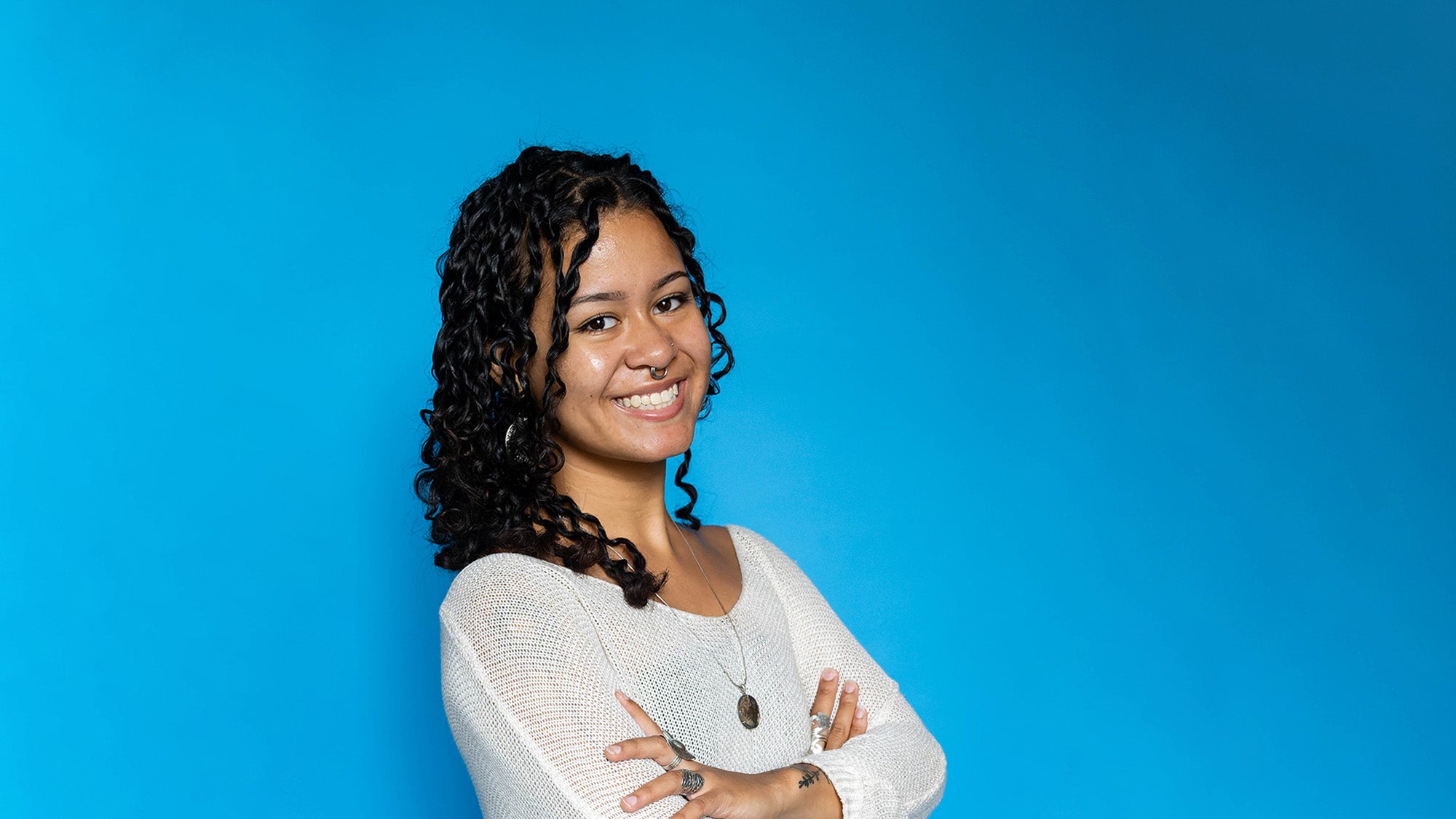 A girl with medium-length dark hair smiles in front of a blue background.