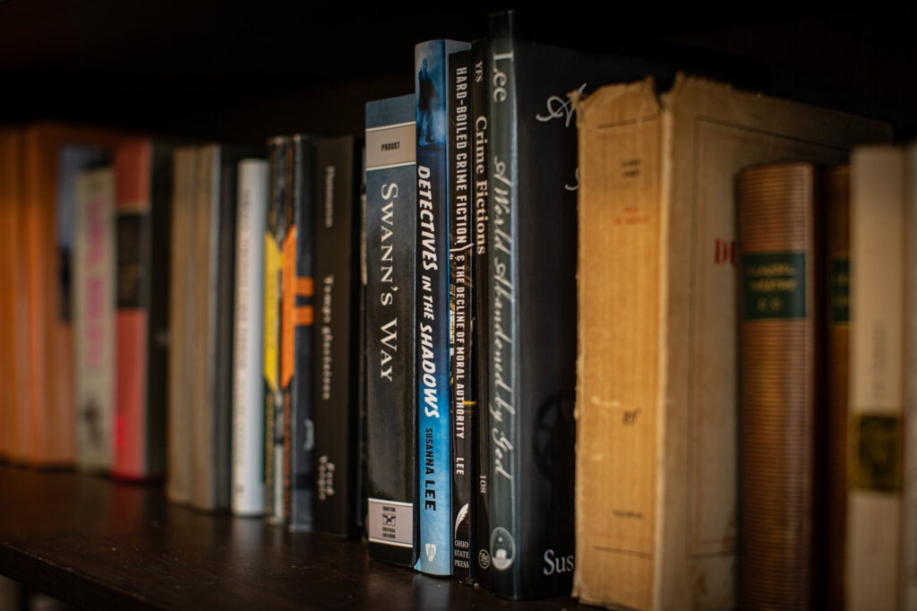 A collection of books on a bookshelf. The most prominent is Swann's Way by Marcel Proust. 