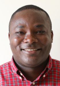 A smiling man with short hair. He wears a red button down shirt. 