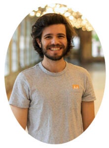 A man with medium-length dark hair smiles inside. 