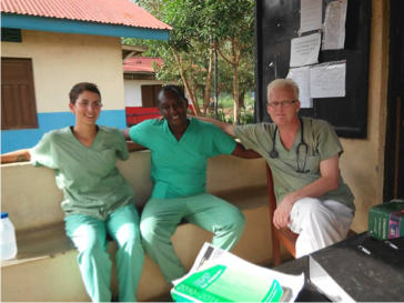 Three doctors in green scrubs sit on a couch outside. 