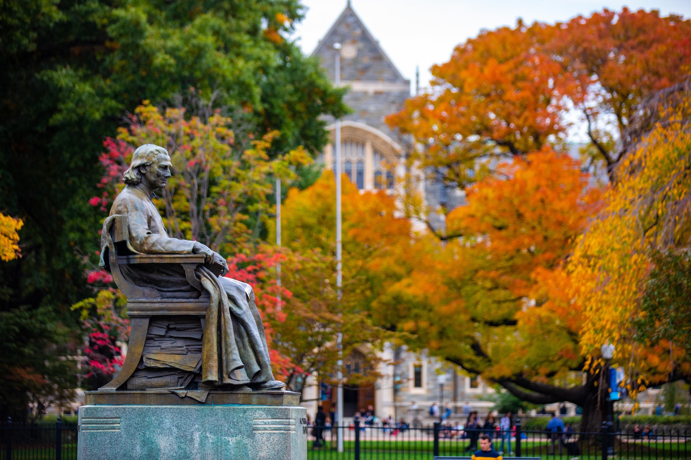 Statue of John Carroll in front of White-Gravenor Hall with autumn leaves in the background