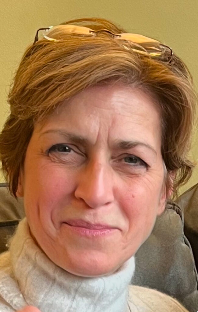 A professor wearing a turtleneck sweater smiling at the camera.