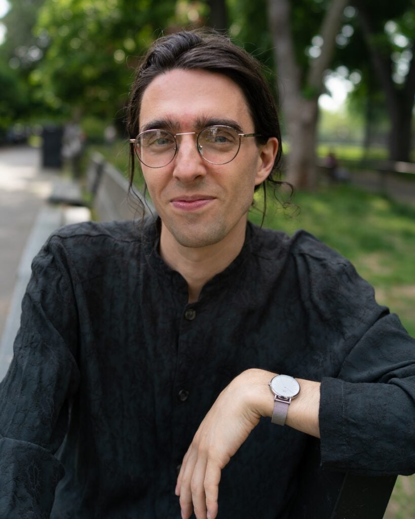 A person wearing a black shirt smiling at the camera.