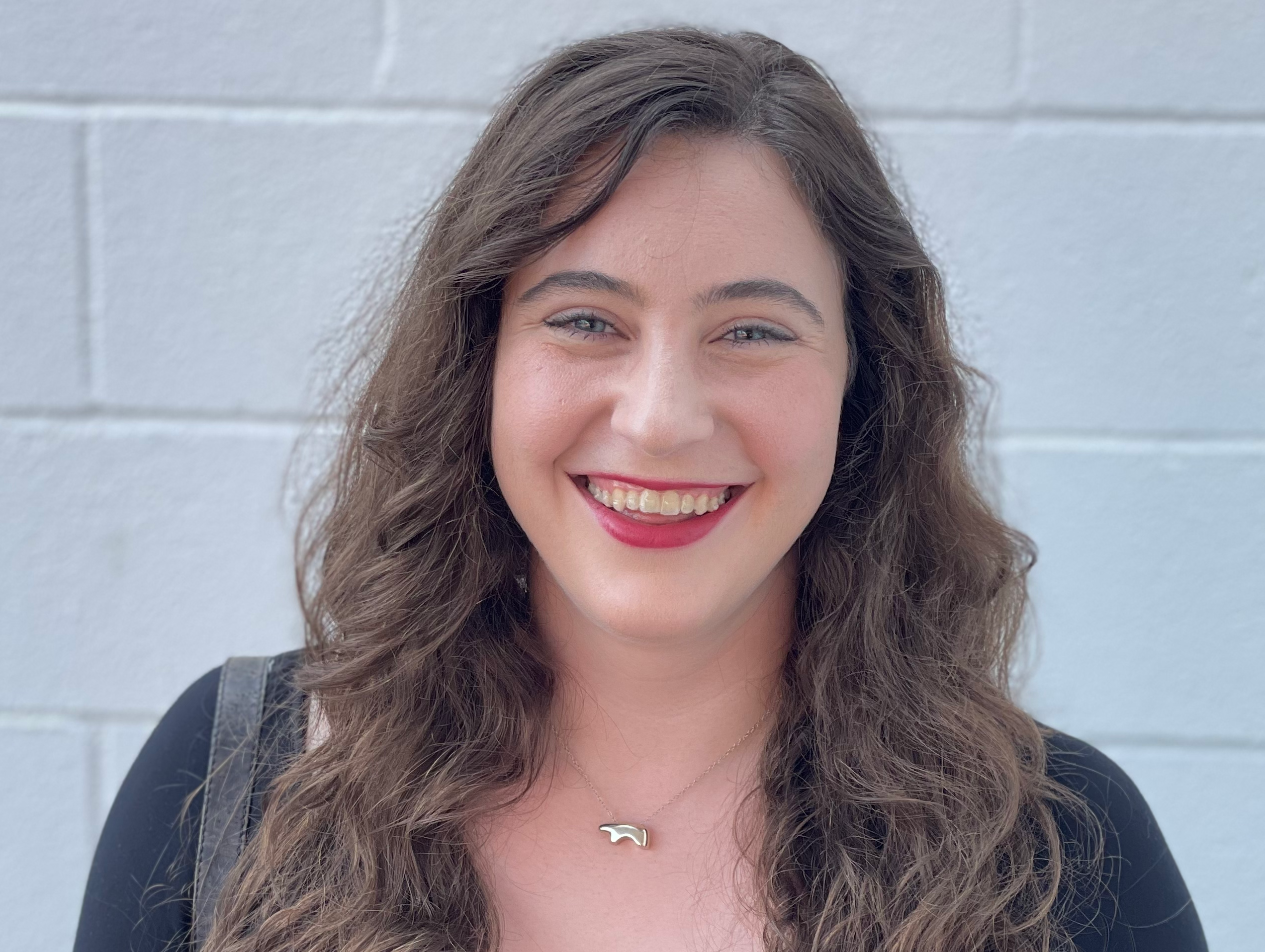 Headshot of a young woman professor smiling, wearing a black shirt