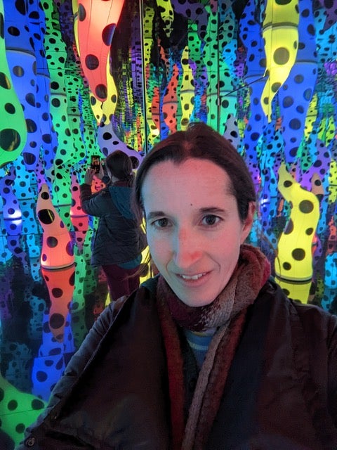 A woman posing for a photo in front of a colorful background.