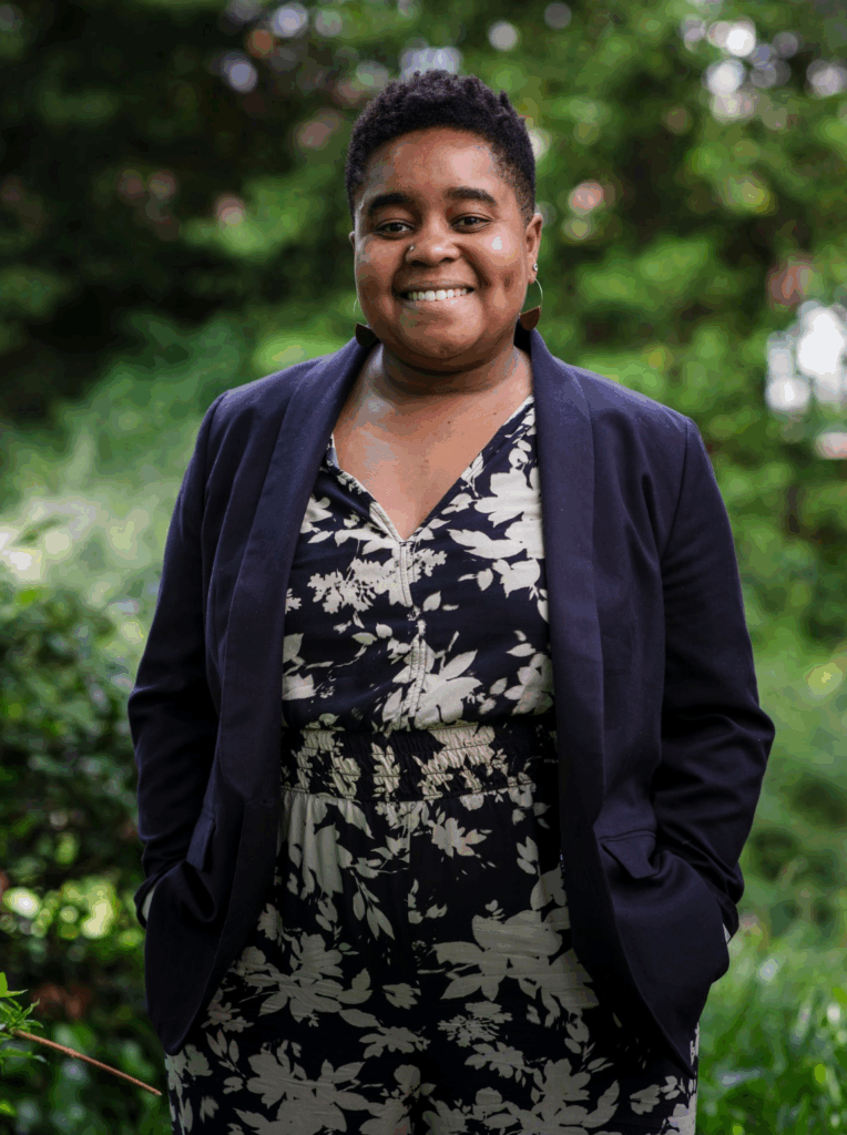 A professor wearing a flower-patterned shirt and jacket, smiling for the camera.