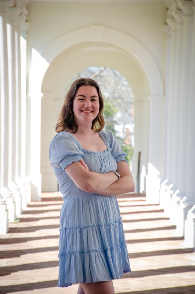 Woman standing with arms crossed, smiling at the camera.