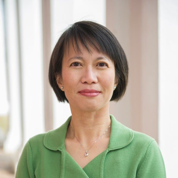A woman wearing a green sweater looking at the camera for a headshot.