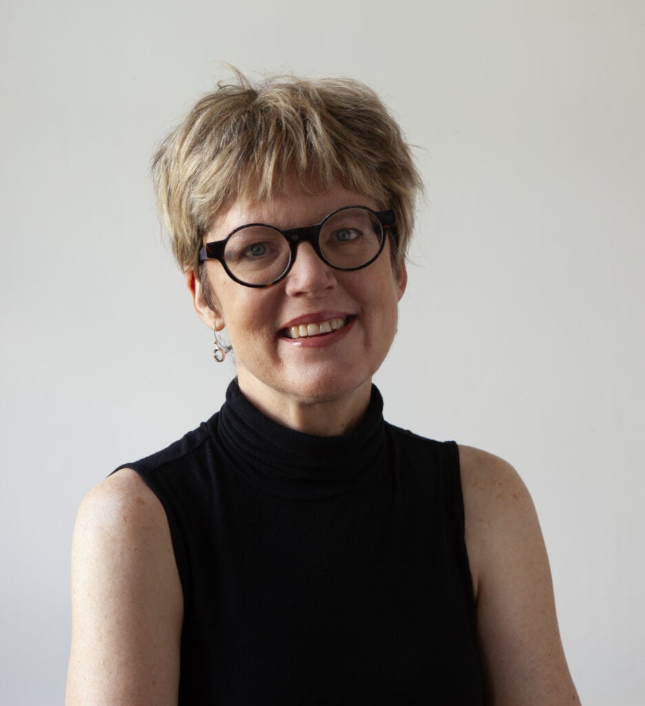 A professor wearing a black shirt and glasses smiling for the camera.