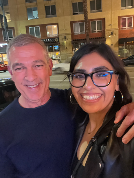 Two people smiling and posing together. The person on the left is a professor and the other is a former student.