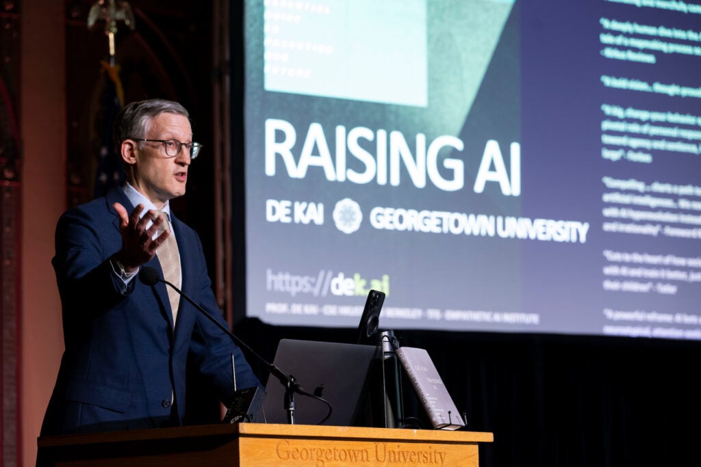 A dean stands in front of a podium and speaks to a crowd