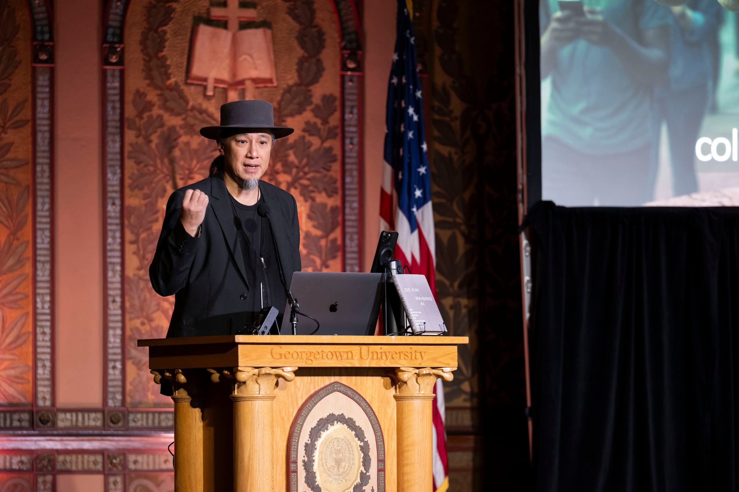 An AI expert standing in front of a podium and speaking to an audience at Gaston Hall