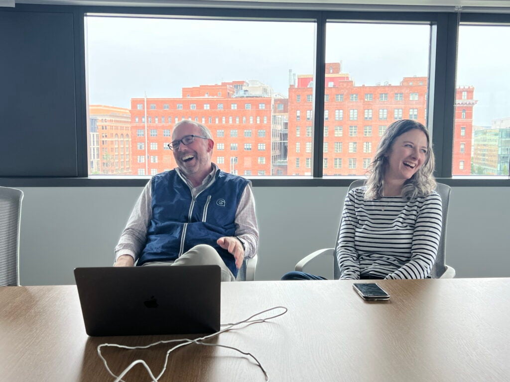Two professors sharing a laugh at a conference room table.