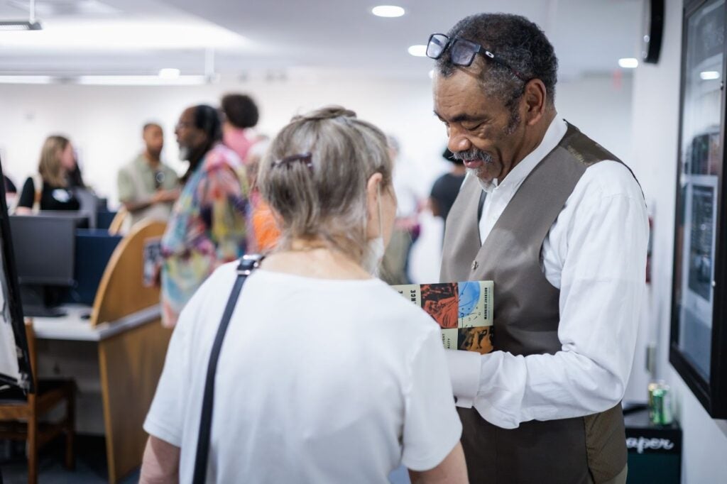 A professor signs books for attendees during the opening reception of his exhibit at Georgetown University’s Lauinger Library.