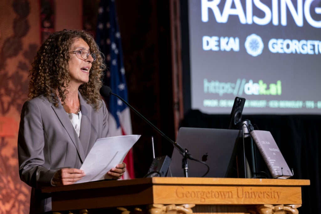 A professor standing in front of a podium and speaking to a crowd