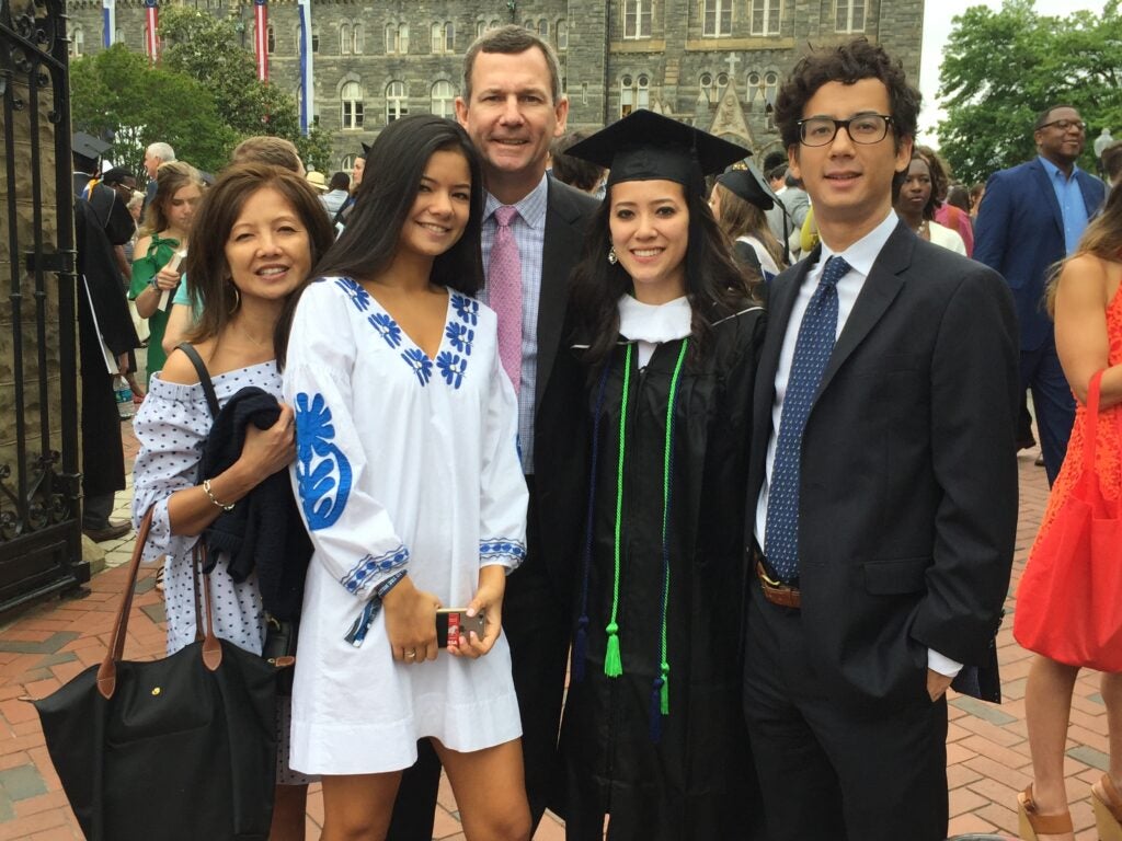 A Georgetown University graduate standing with her two siblings and parents