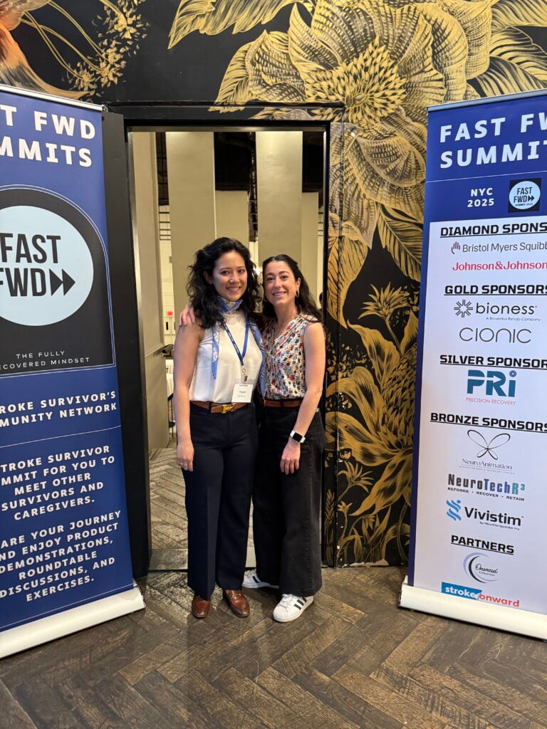 Two women smile and pose together at an event, one of them a college friend visiting the other at a summit in New York City