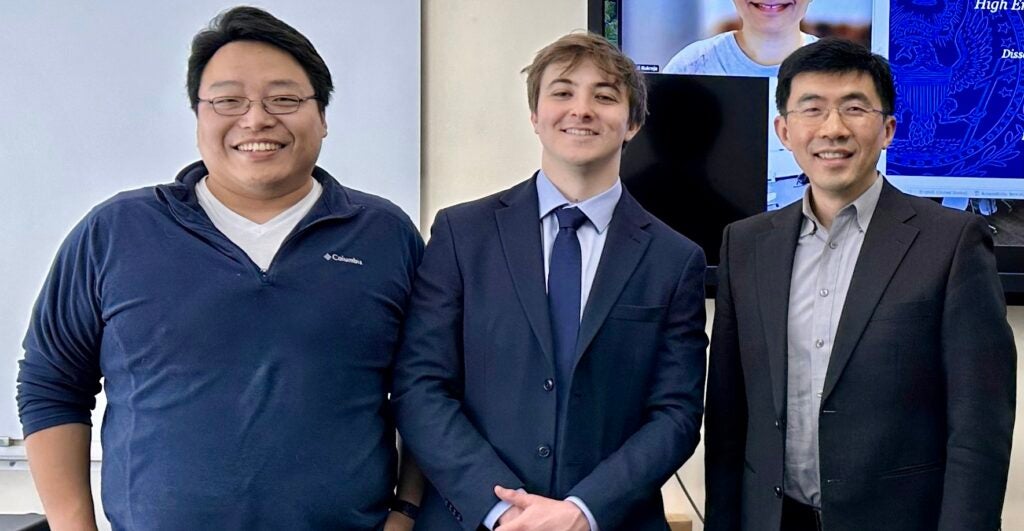 A Ph.D. student wearing a student with his professors at his thesis defense.