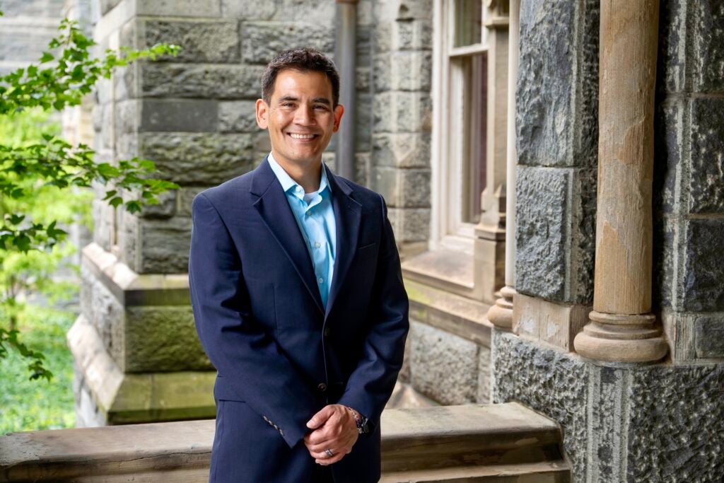 A professor wearing a suit jacket and dress shirt standing in front of a building at Georgetown University