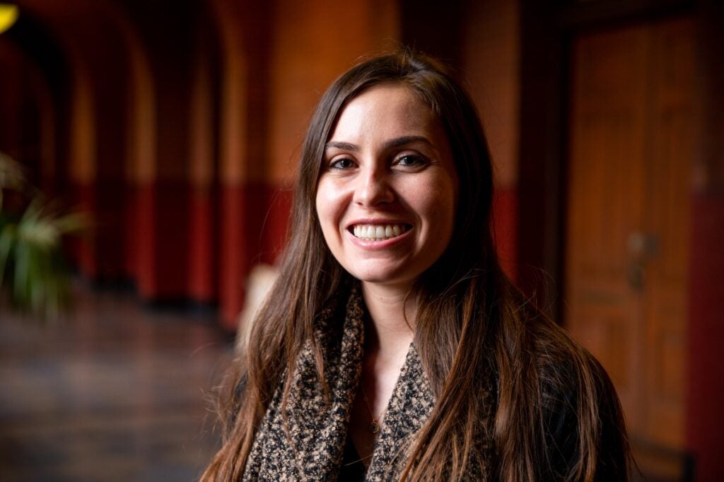 A Ph.D. graduate with long brown hair smiles for a portait.