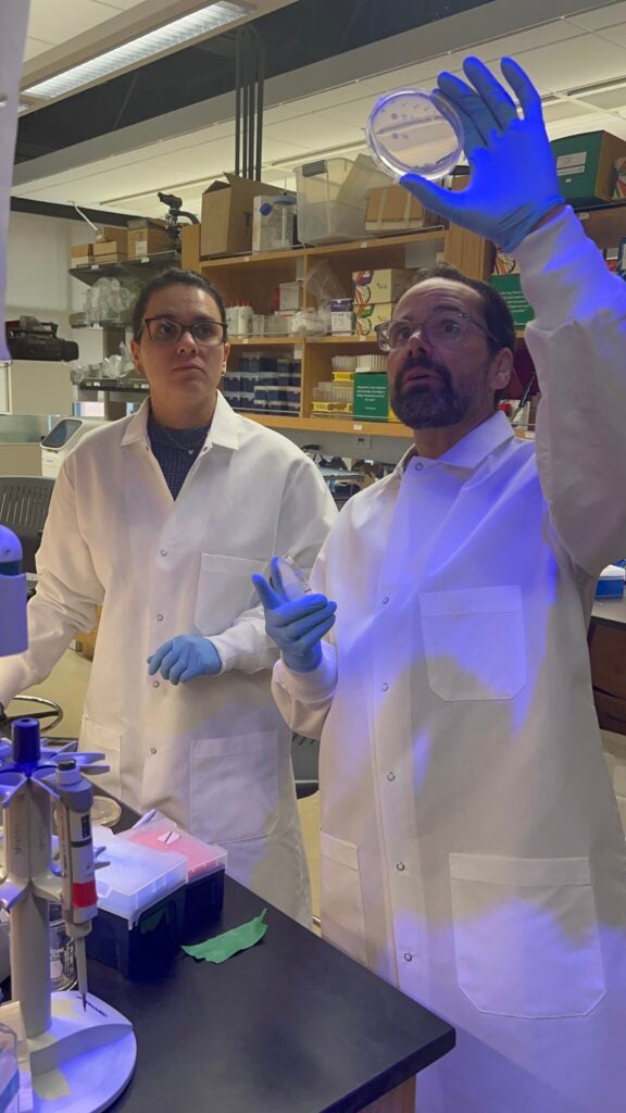 A professor and a Ph.D. student wearing lab coats and a conducting an experiment in a lab.