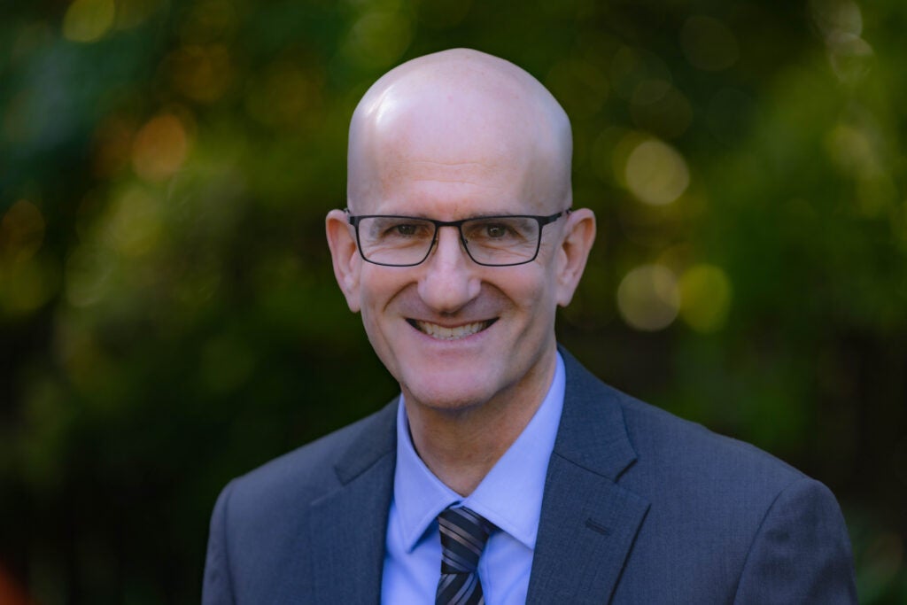A economics professor wearing a suit and tie smiling 