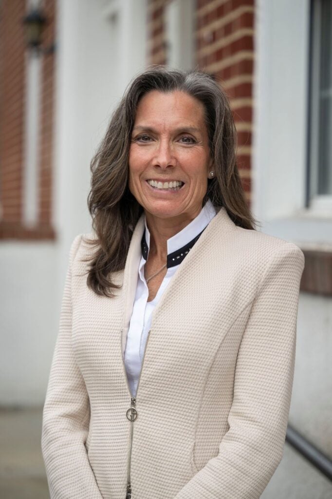 An associate dean wearing a jacket and shirt smiling for the camera