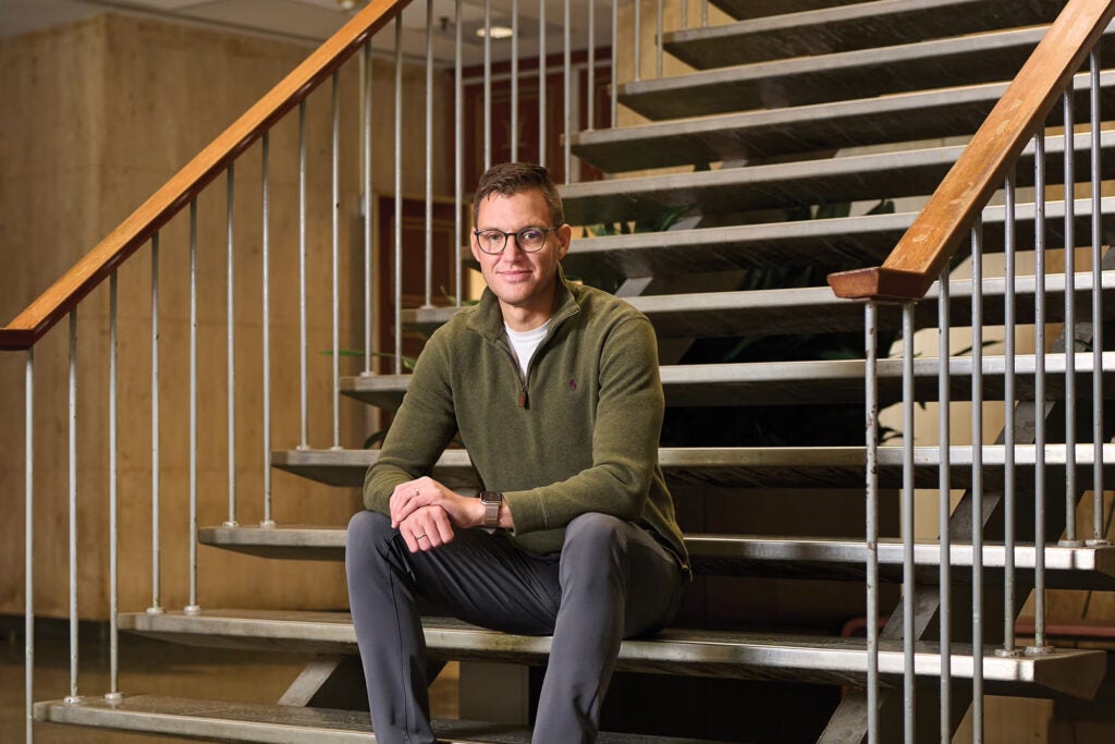 A professor of psychology wearing a green sweater sitting on stairs
