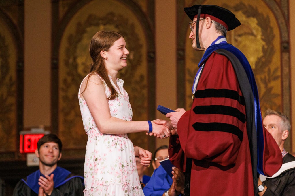 A student shaking hands with the dean of the College of Arts and Sciences