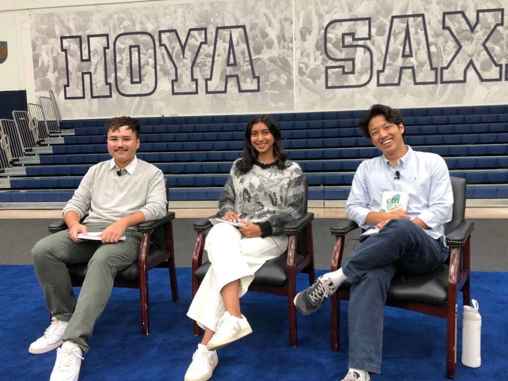 Three students sitting in chairs at a book event