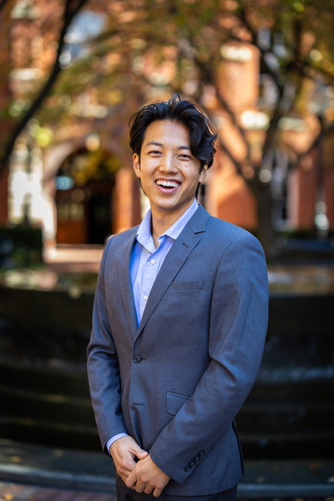A student wearing a jacket and dress shirt smiling