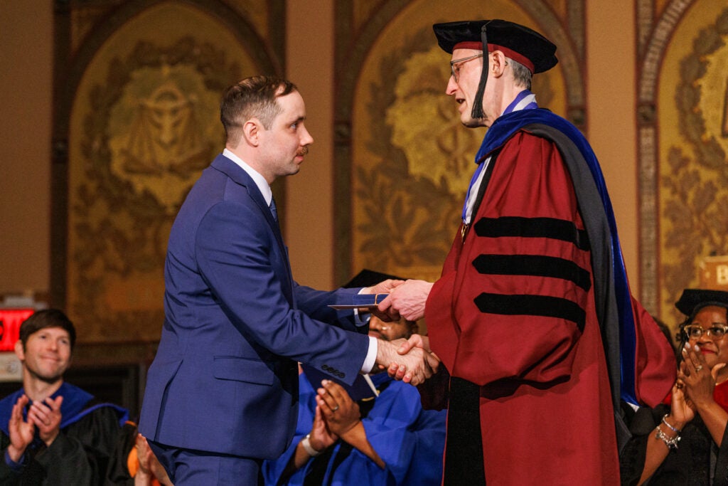 A student shaking hands with the dean of the College of Arts and Sciences