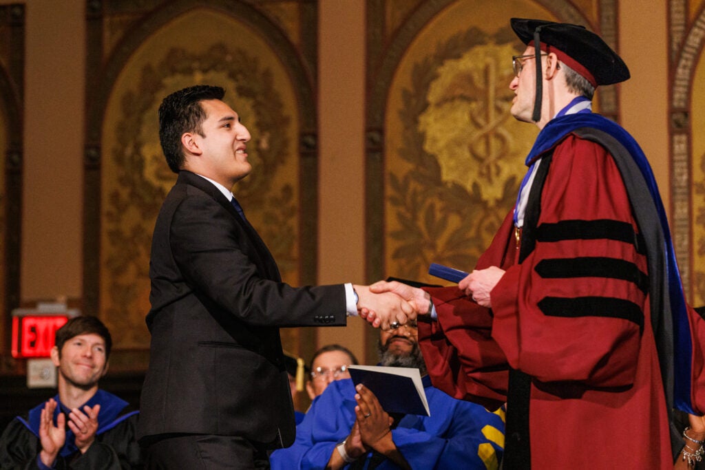 A student shaking hands with the dean of the College of Arts and Sciences