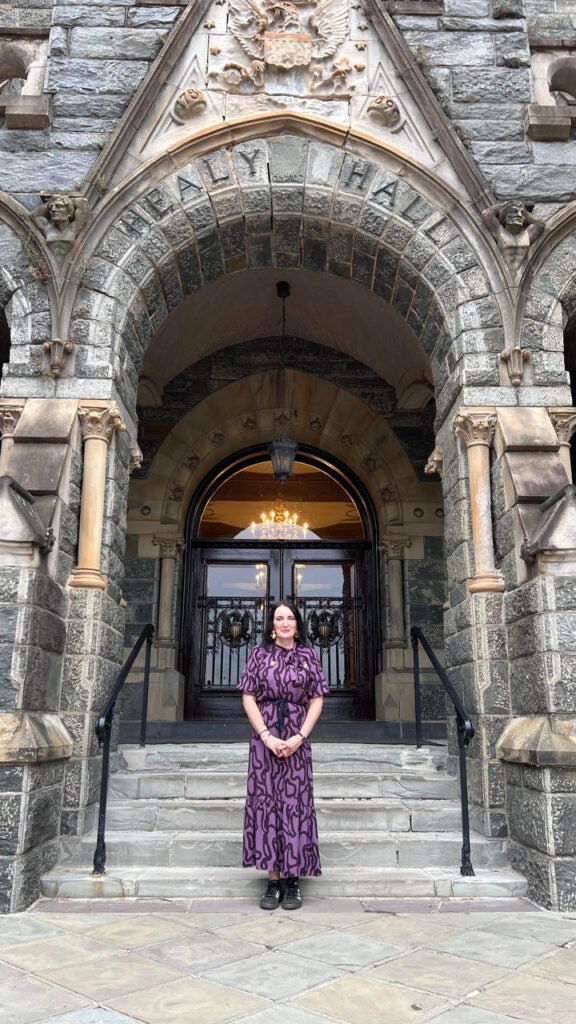 A woman in a purple and black dress standing in front of Healy Hall