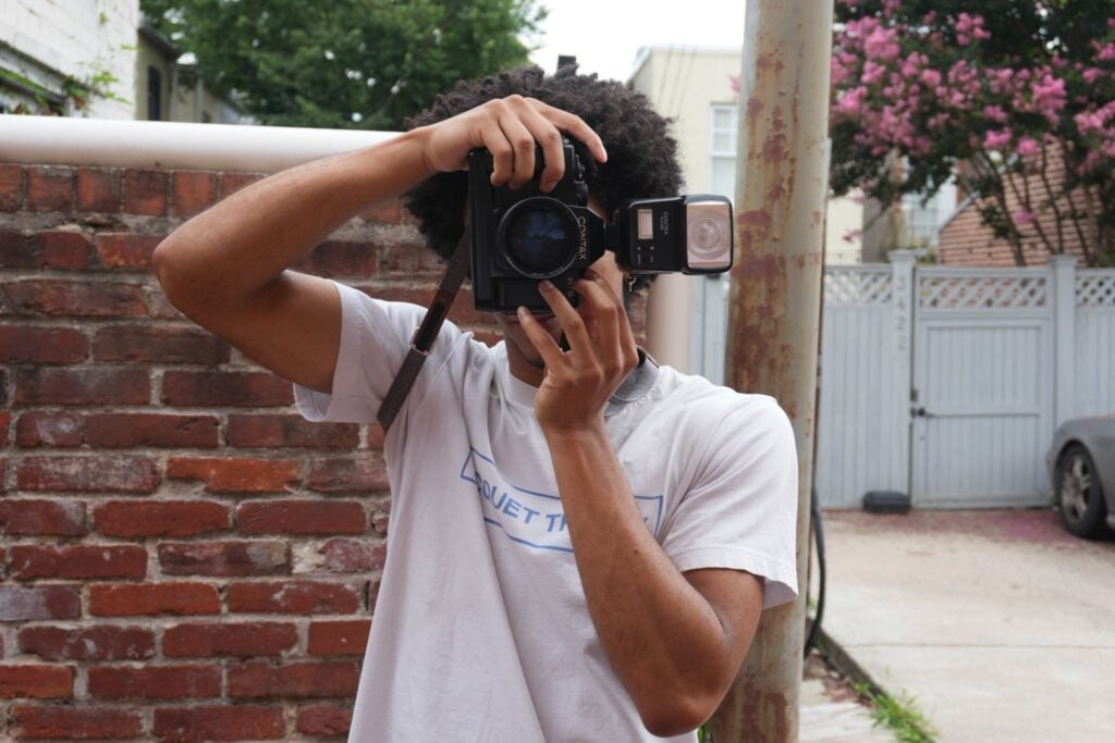 A Georgetown student holding a camera and looking through the lens.