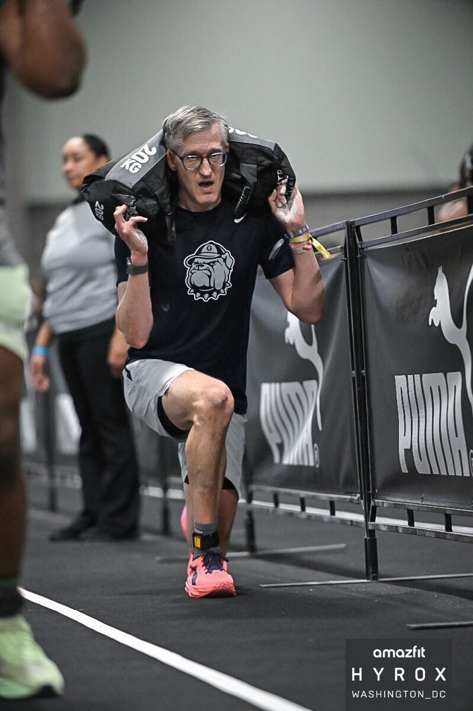A Georgetown University dean doing a farmer's carry exercise during a fitness competition.