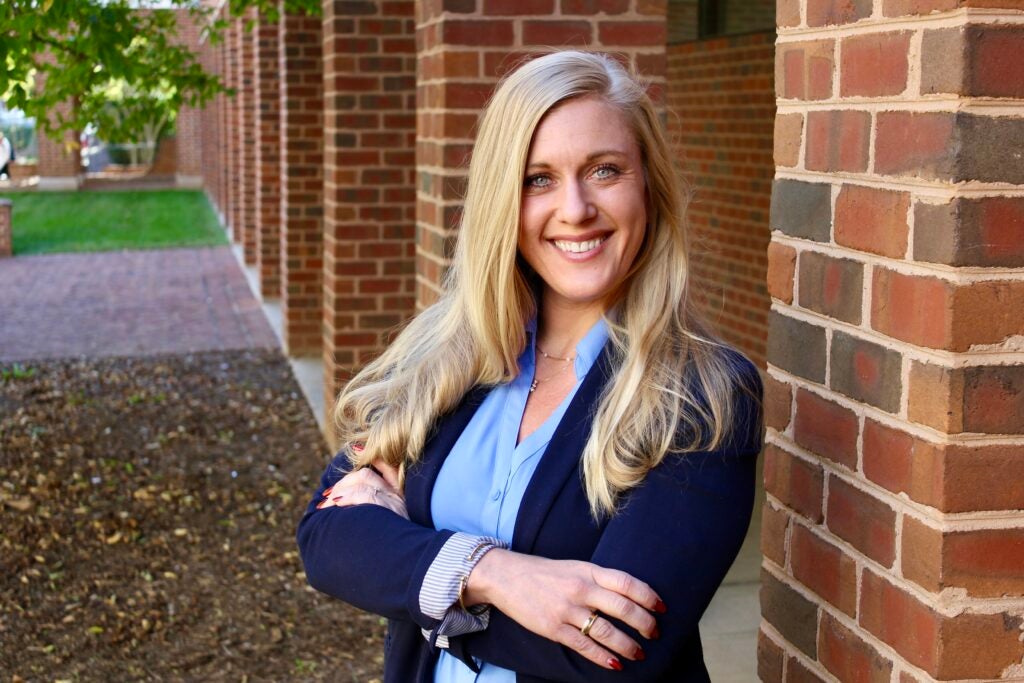 Headshot of a Georgetown University professor smiling in front of a brick building.