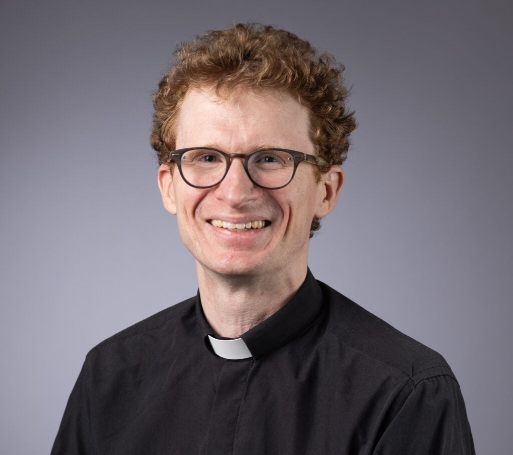 Headshot of a Georgetown University professor and Jesuit priest smiling in front of a neutral background.