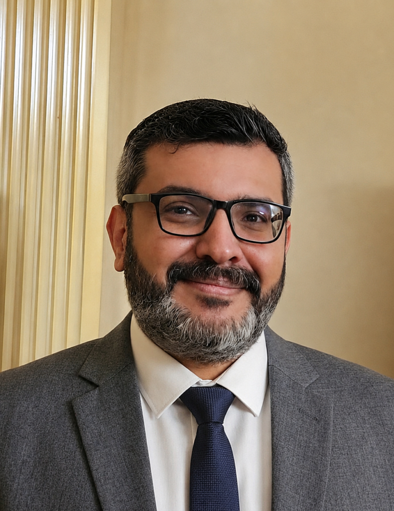 A professor wearing glasses and a gray jacket and blue tie.