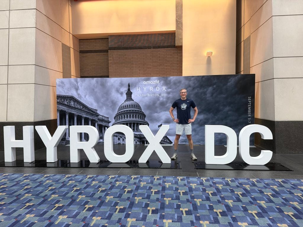 A Georgetown University dean stands in front of a banner for a fitness race.