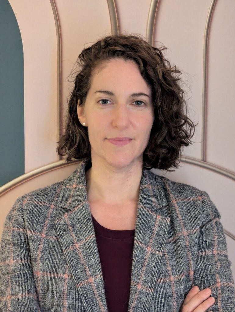 Headshot of a Georgetown University professor posing in front of a neutral background with her arms crossed.